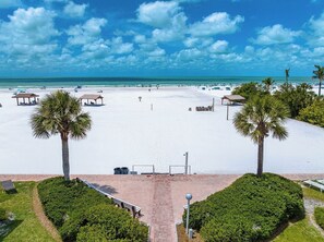 Ein Strand mit weißem Sand, Palmen und blauem Himmel.
