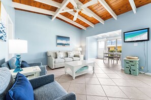 A living room with a white coffee table, grey sofas, and a television on the wall.