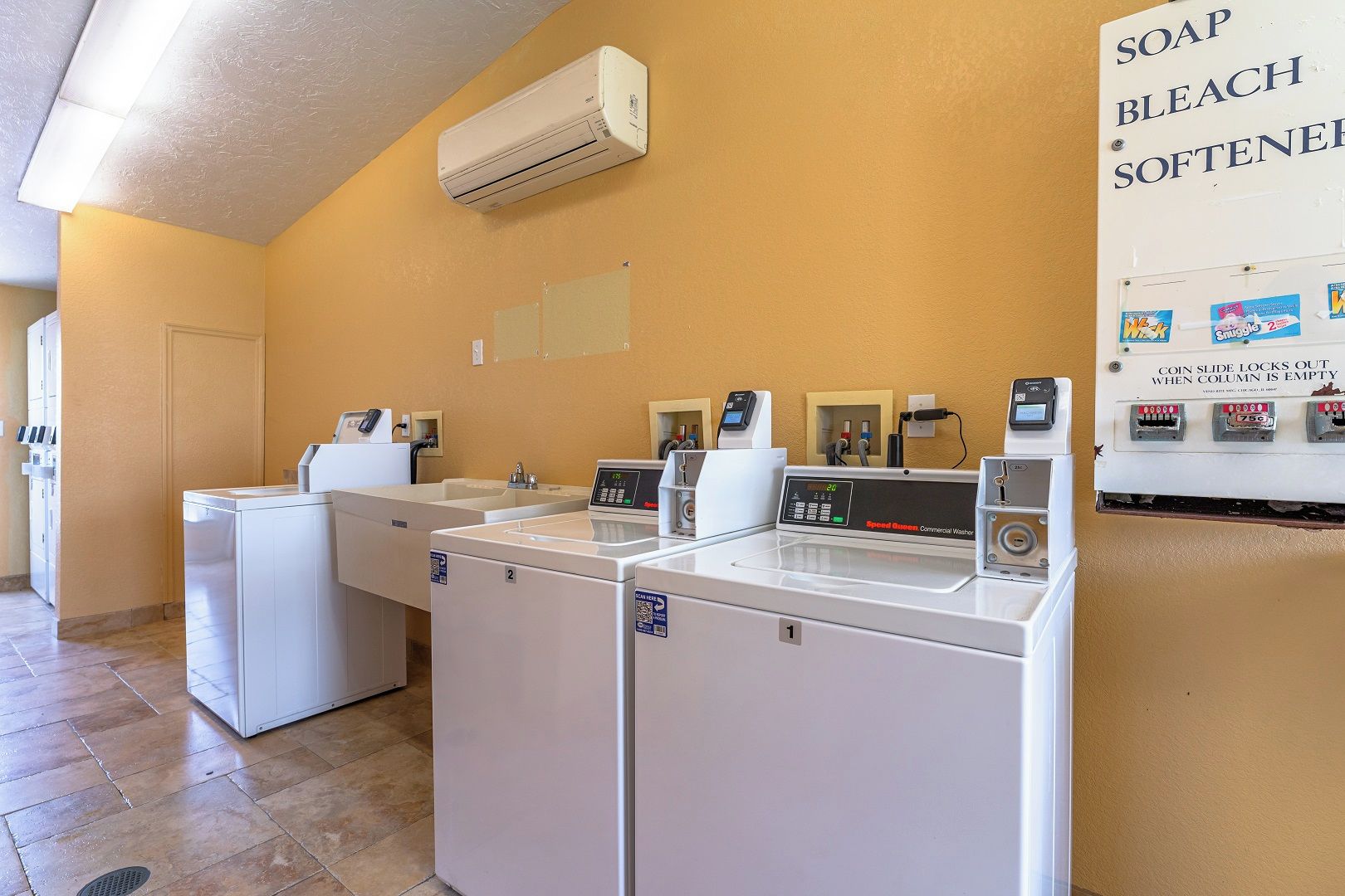 Une buanderie d’hôtel équipée de plusieurs machines à laver et d’un sèche-linge à pièces.