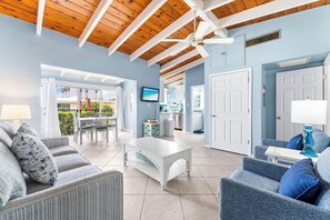 A spacious living area with a high ceiling, a white coffee table, grey sofas, and a blue armchair. - Casa Mar By Beachside Management (Siesta Key)