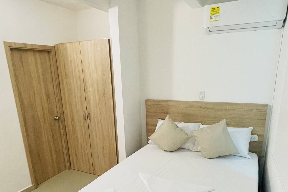 Une chambre à coucher avec un lit, une armoire en bois et un luminaire au plafond.