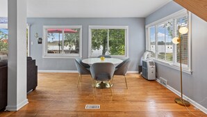A dining area with a round table, gray chairs, and a yellow vase. - Park Lake Getaway (East Lansing)