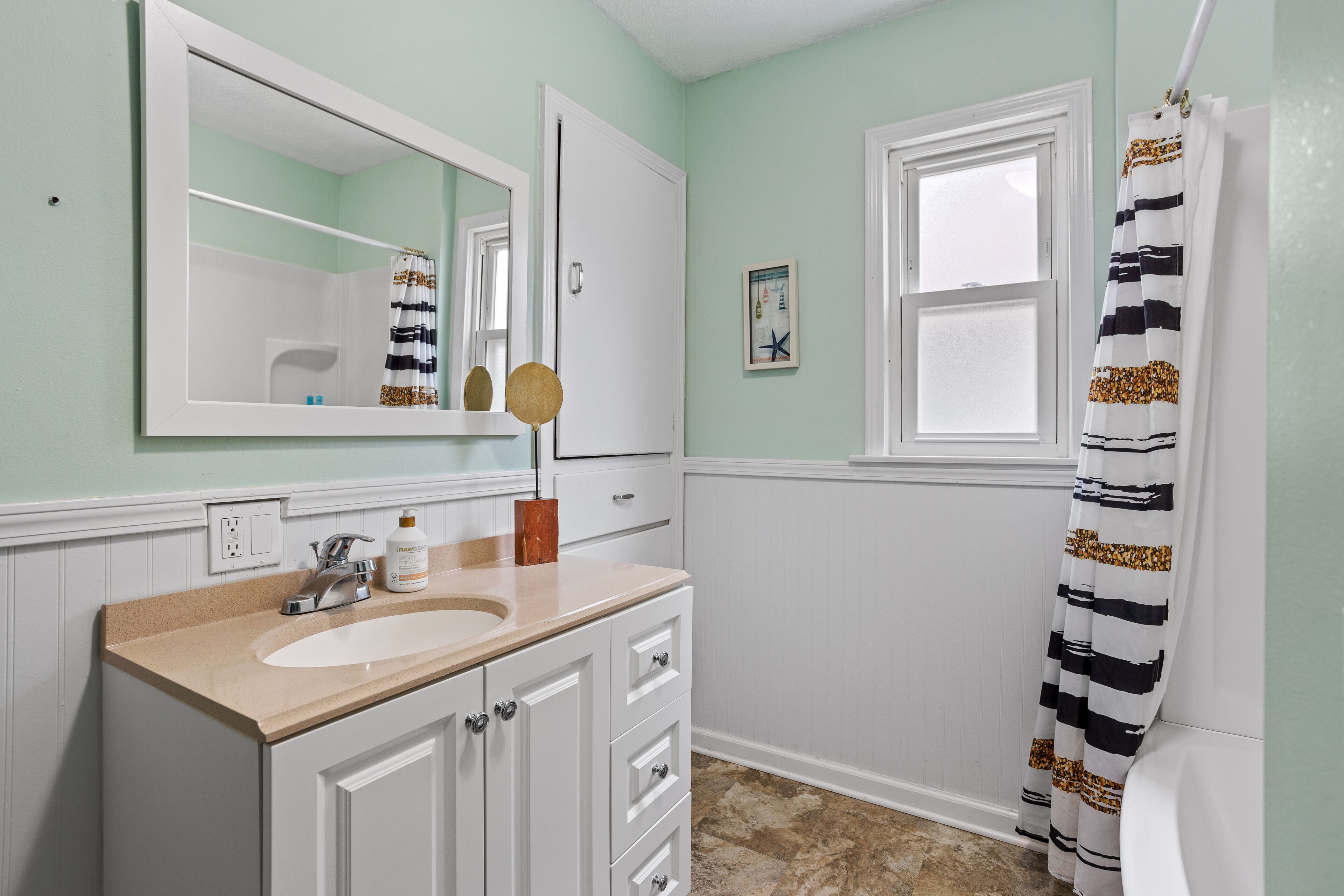 Une salle de bain avec un meuble-lavabo blanc, un miroir, un lavabo et un rideau de douche.