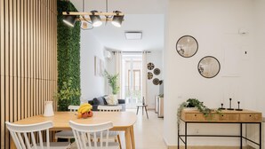 A modern dining area with a wooden table, white chairs, and a green wall.