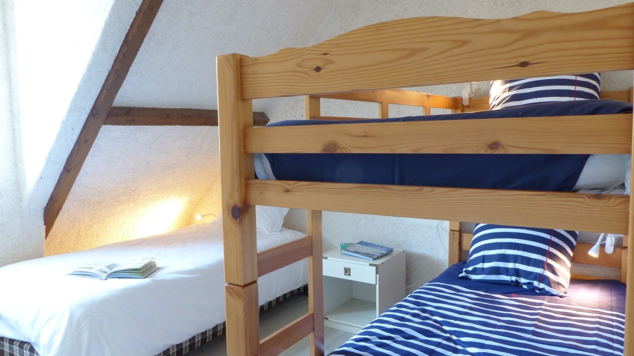 A dormitory-style room with bunk beds, a small desk, and a window.
