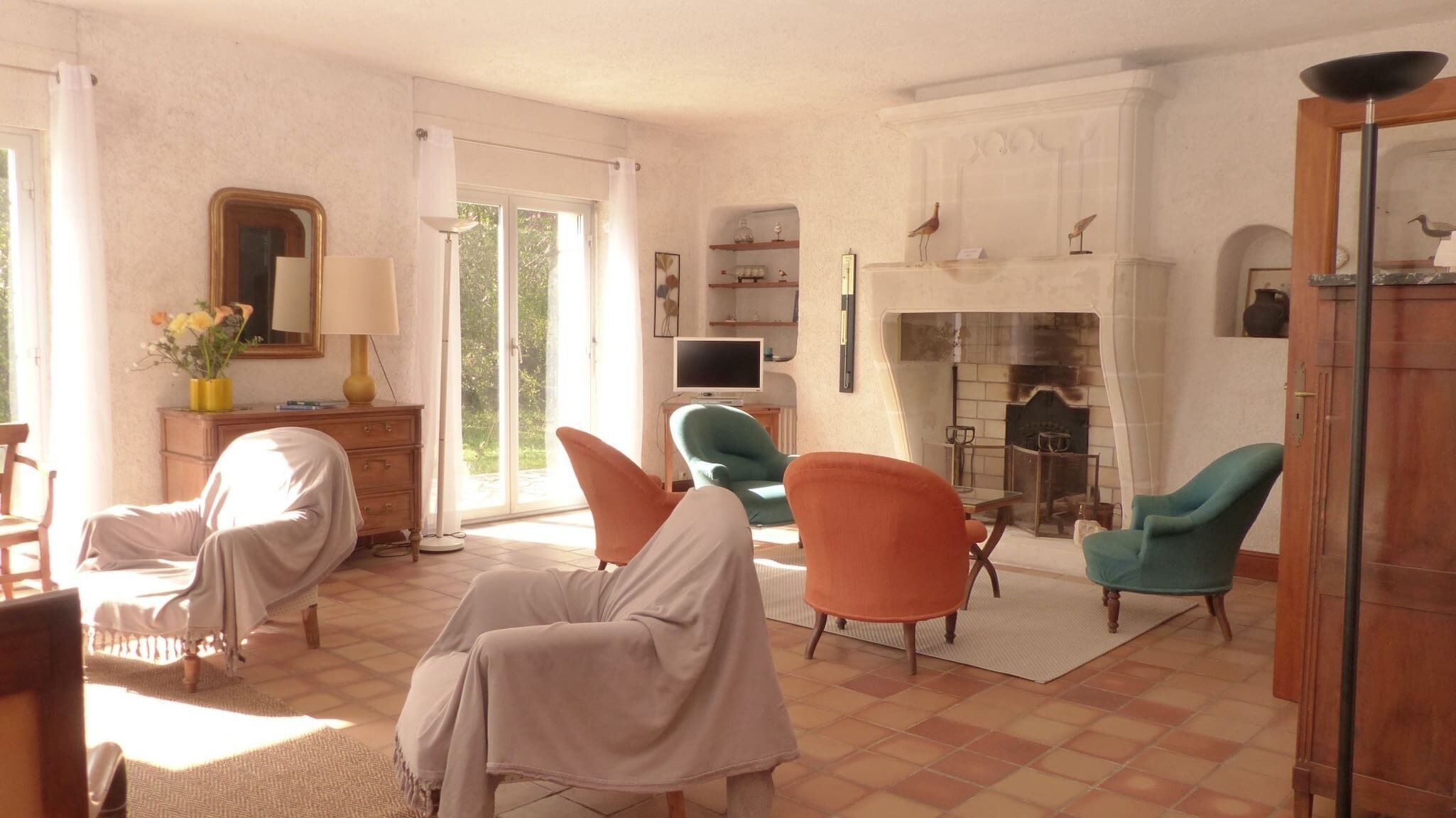 A living room with a fireplace, a television, and a window with curtains.
