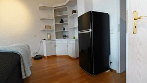 Una cocina compacta con armarios blancos, un refrigerador negro y una pequeña encimera.