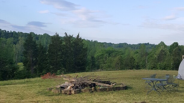 A gravel parking area with a picnic table and chairs, surrounded by a grassy field and trees. - Secluded RV Camper Spot (Thomasville)