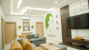 A modern living room with a sofa, coffee table, TV, and decorative wall art. - Tokyo Apartments  (Abuja)