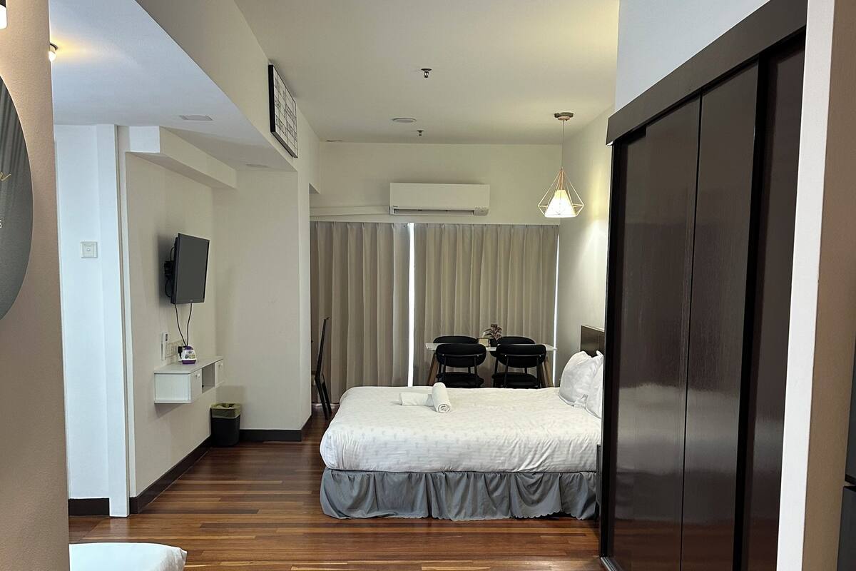 Een hotelkamer met een bed, een bureau, een stoel, een televisie en een kledingkast.