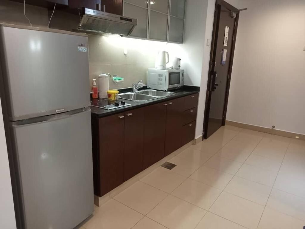 A compact kitchen with a refrigerator, microwave, and sink.