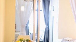 A modern hotel room with a dining area, a bed, and a view of the balcony. - Homesuite' Home at The Shore KK (Kota Kinabalu)