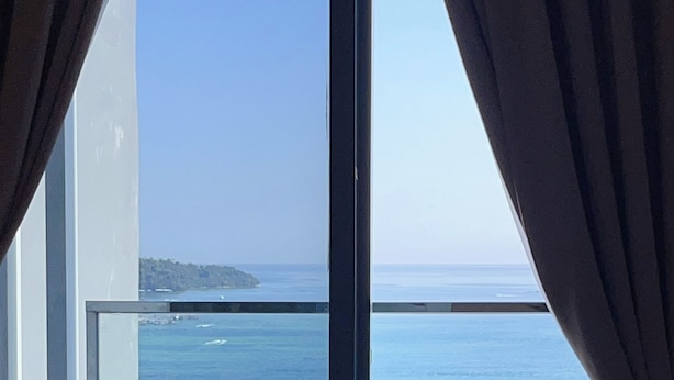 A balcony with a chair and a view of the ocean. - Homesuite' Home at The Shore KK (Kota Kinabalu)