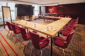 A conference room with a long table, red chairs, and a carpeted floor. - Van der Valk Hotel Paris CDG Airport (Roissy-en-France)