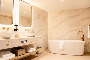 A modern bathroom with a freestanding bathtub, a double sink vanity, and a large mirror. - Van der Valk Hotel Paris CDG Airport (Roissy-en-France)