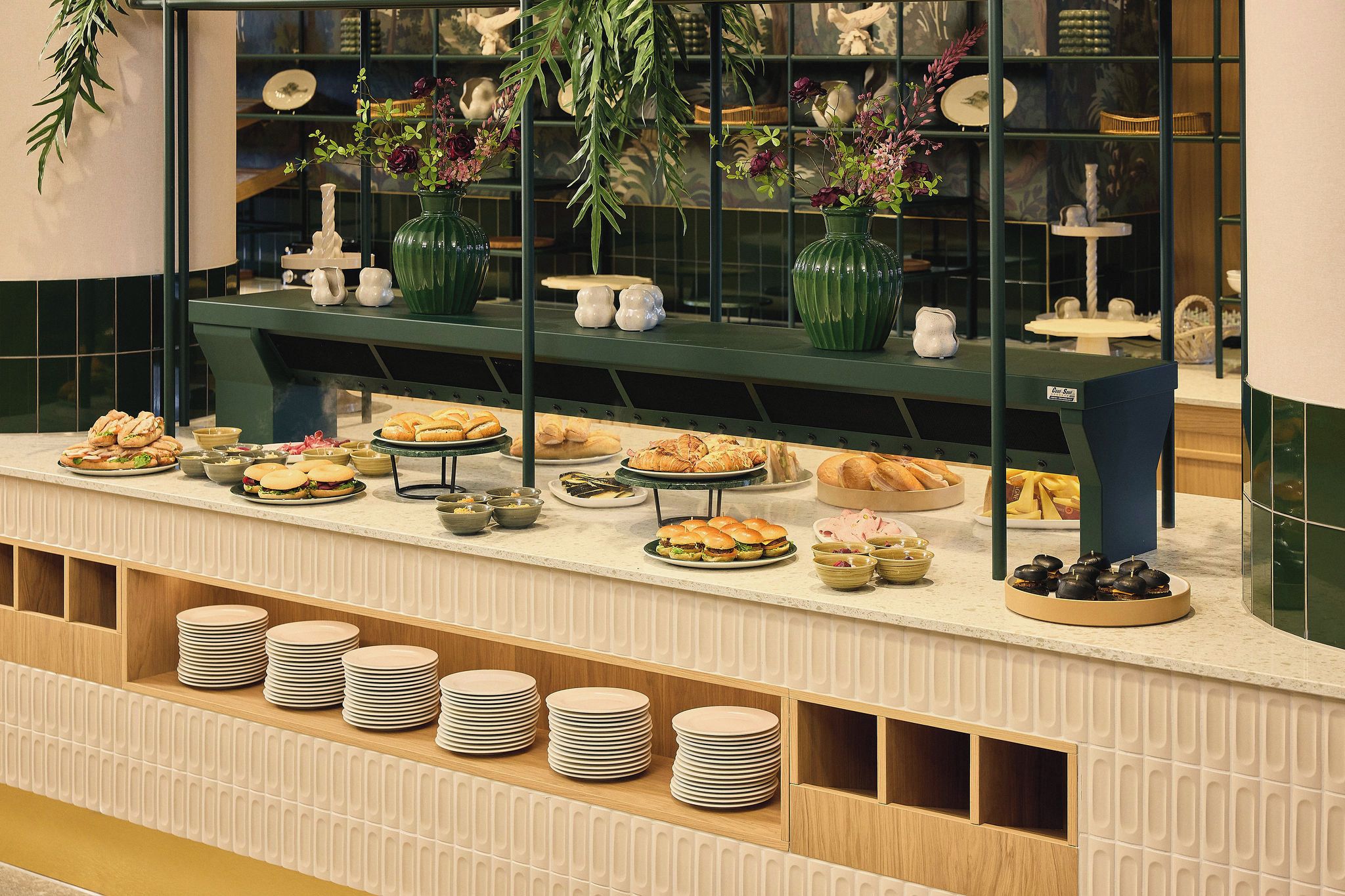 A buffet setup with various food items and a green decorative display.