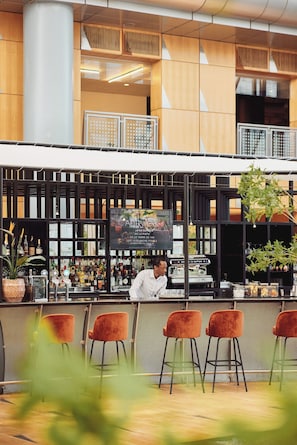 A bar area with a bartender, bar stools, and a menu board.