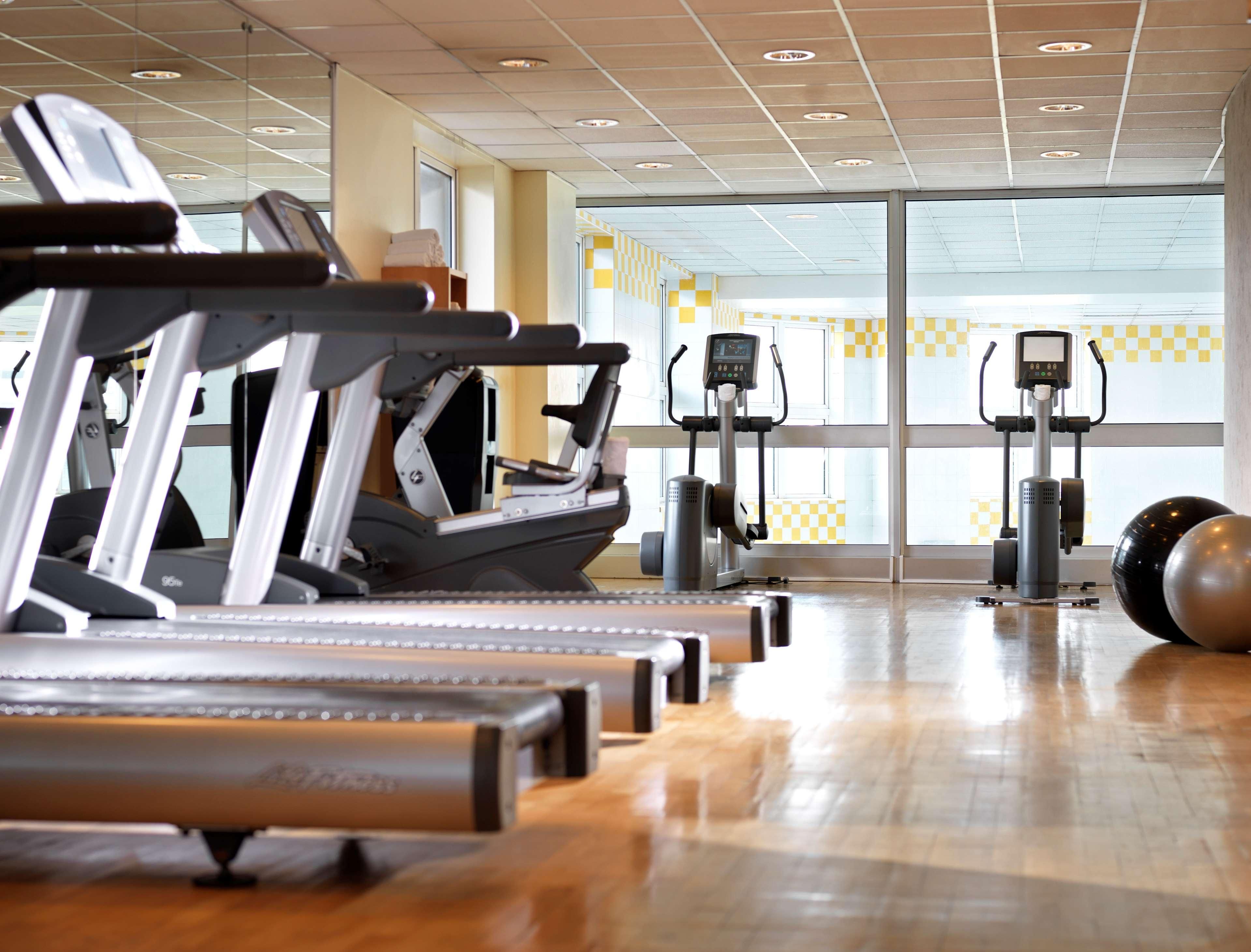 Academia com esteiras, elípticos e bolas de exercício.