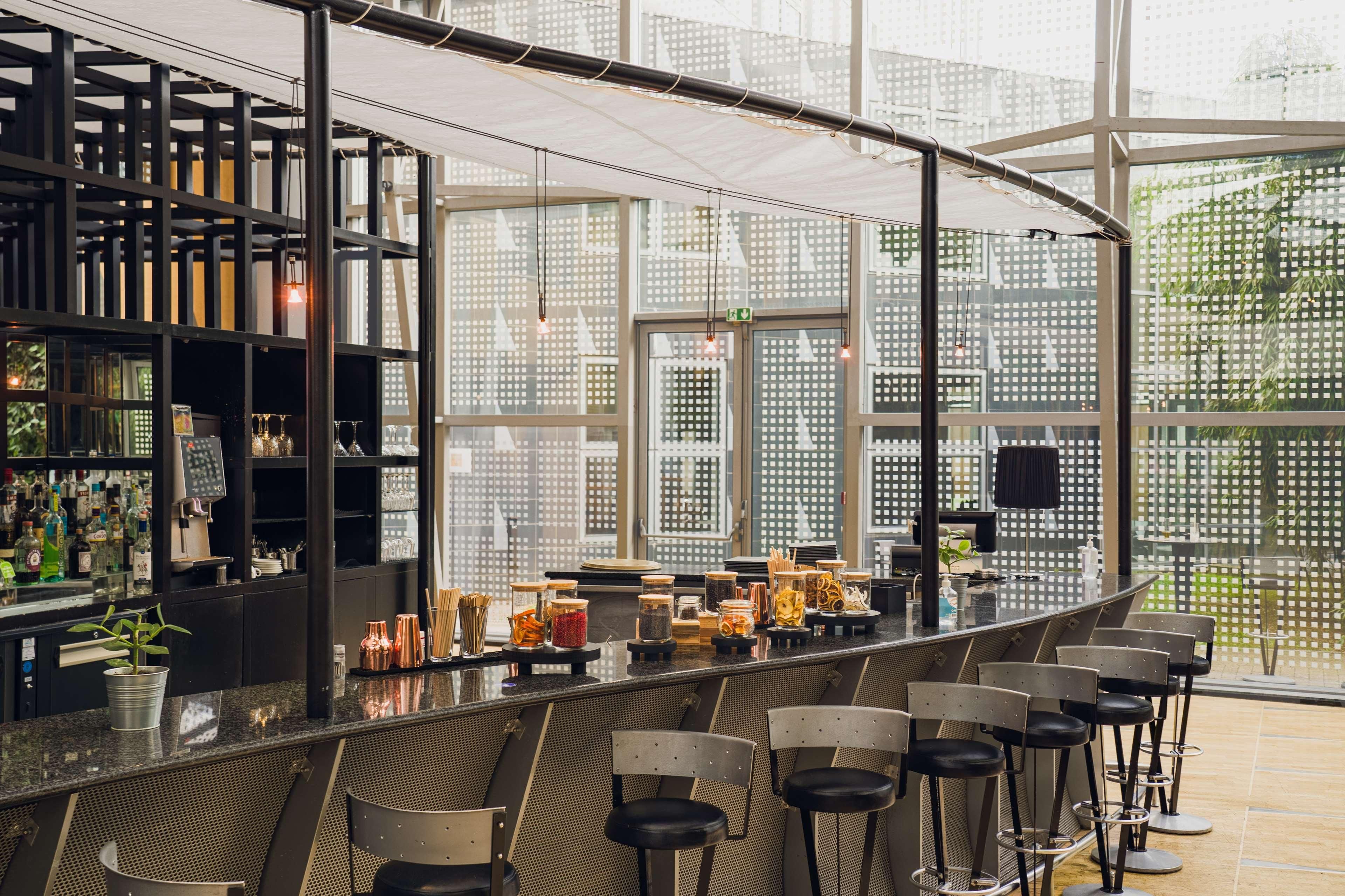 Un bar moderno con una barra curvada, varios taburetes y vistas a la ciudad a través de amplias ventanas.