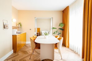 A modern dining area with a white table, yellow chairs, and a large mirror above the table.