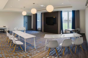 Une salle de conférence équipée d’une grande table, de chaises, d’un téléviseur et d’un tapis à motifs.