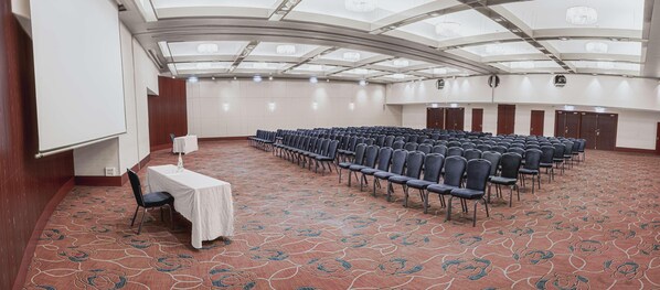 A conference room with rows of chairs, a white table with a cloth, and a patterned carpet. - Van der Valk Hotel Paris CDG Airport (Roissy-en-France)
