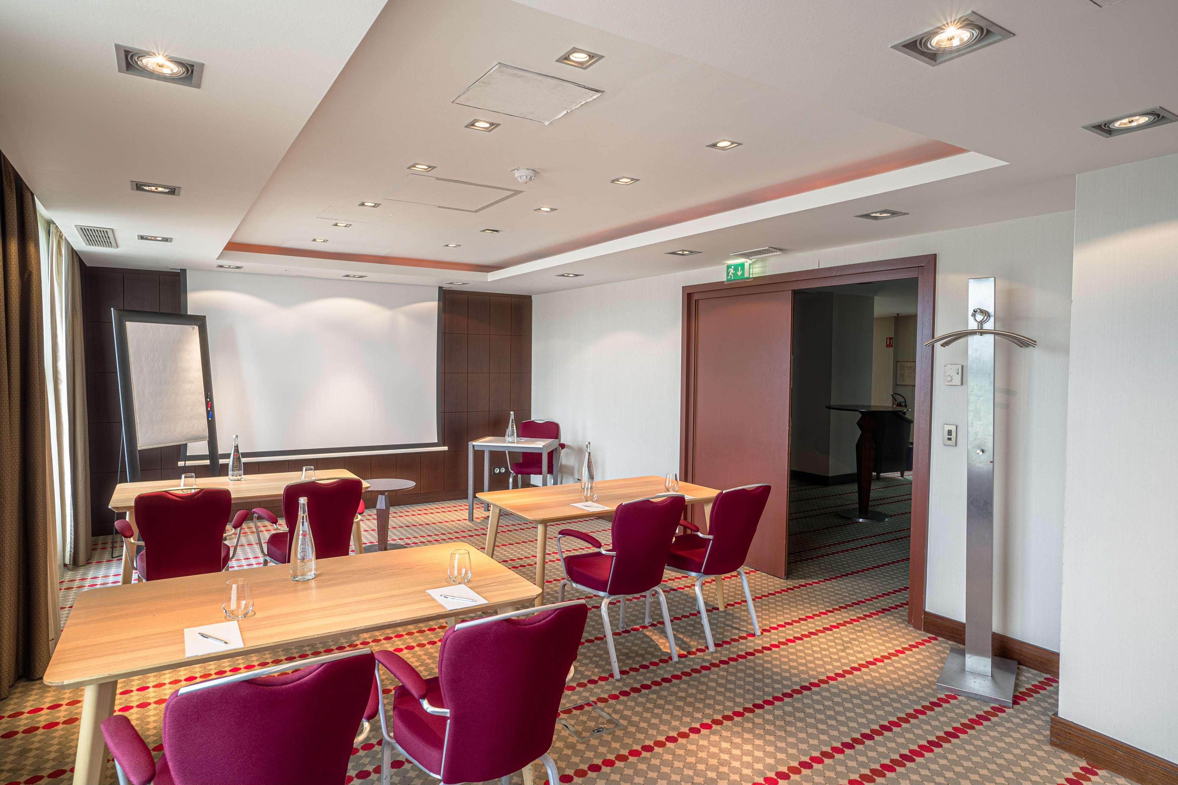 A conference room with tables, chairs, and a projector screen.