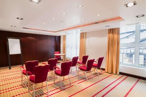 A conference room with red chairs, a whiteboard, and a large window with curtains. - Van der Valk Hotel Paris CDG Airport (Roissy-en-France)