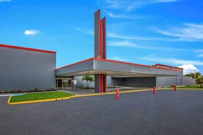 A modern building with a flat roof, a vertical red structure, and a covered entrance area. - OYO Hotel Orlando Airport (Orlando)