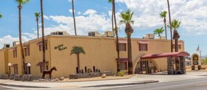 Guests can relax in a covered outdoor seating area amidst palm trees and a decorative horse statue.