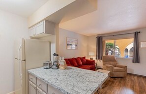Relax in this cozy space with a kitchenette, sofa, and armchair, offering a view of the outside.