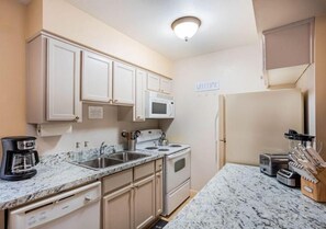 Compact kitchen with a coffee maker, toaster, microwave, and refrigerator.