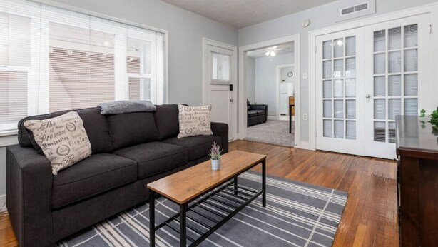 A living room with a dark sofa, a wooden coffee table, and a striped rug. There are white doors with glass panels and a ceiling fan. - Historic Avenues Downtown Loft (Salt Lake City)