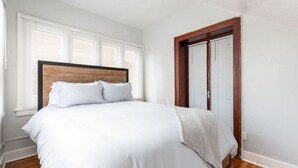 A bedroom with a large bed, white bedding, a wooden headboard, and a window with blinds. - Historic Avenues Downtown Loft (Salt Lake City)