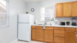 A kitchen with wooden cabinets, a white refrigerator, a sink, and a clock on the wall. - Historic Avenues Downtown Loft (Salt Lake City)
