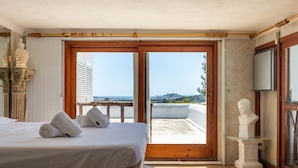 Ein Hotelzimmer mit Bett, Meerblick und einer Büstenstatue.