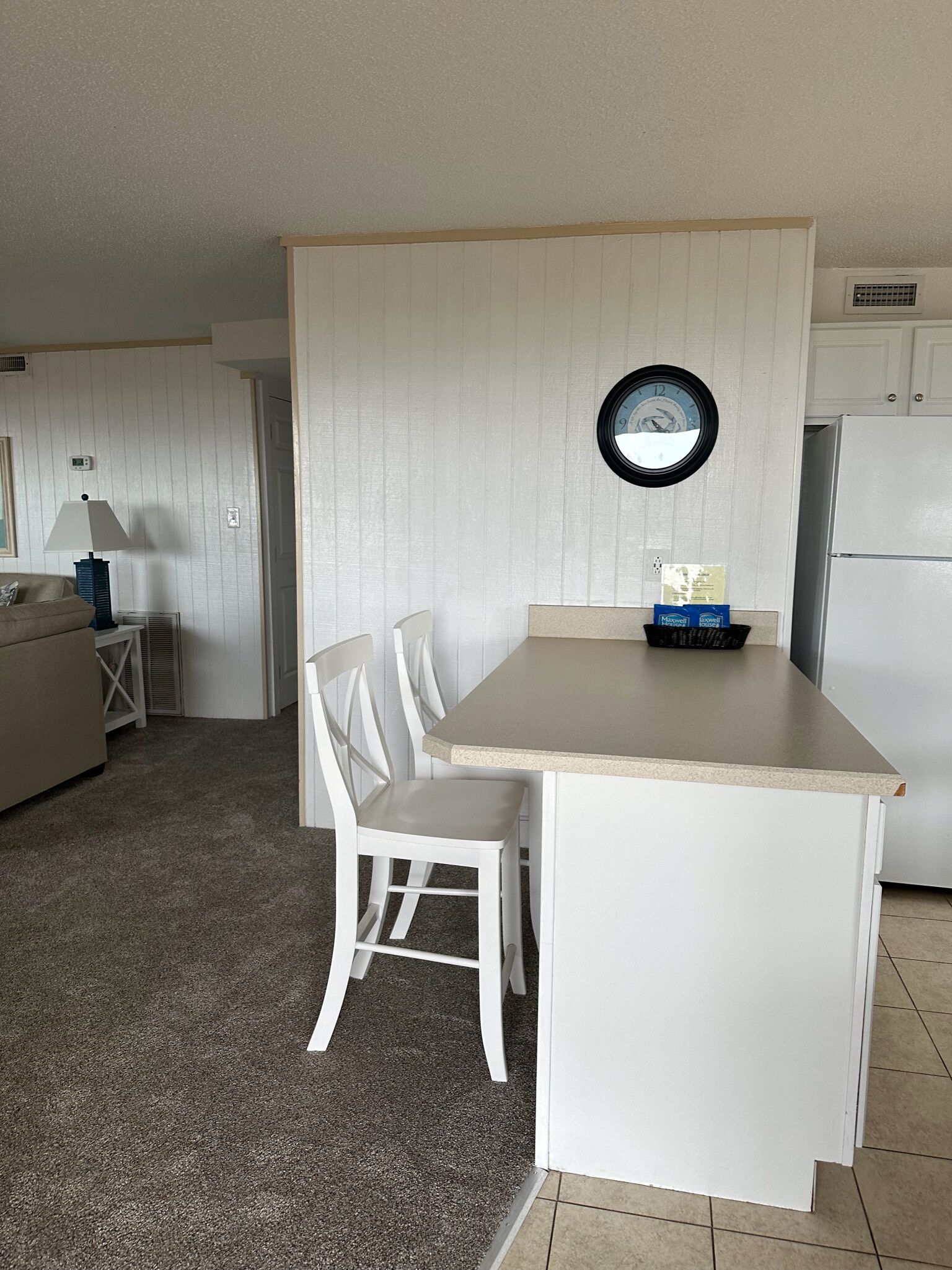 A compact kitchen with a small island, white cabinetry, and a clock on the wall.