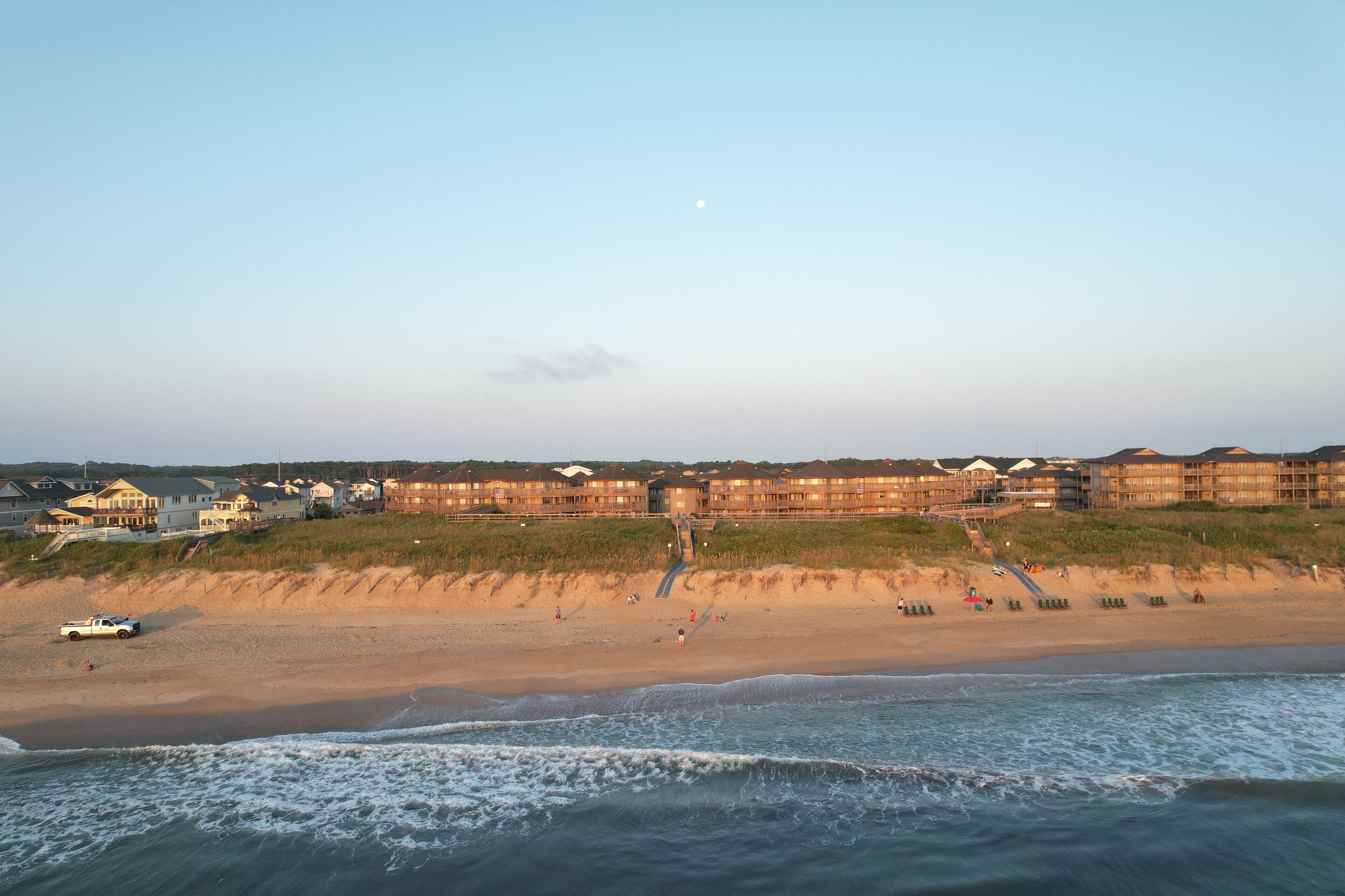 A beachfront hotel with multiple buildings, a sandy beach, and a view of the ocean.