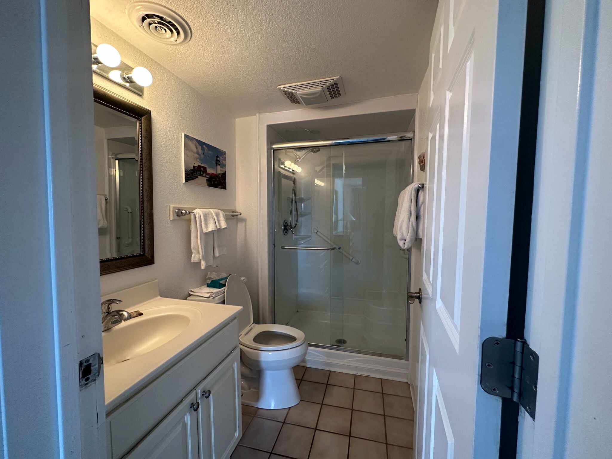 A bathroom with a glass shower enclosure, a white sink, and a toilet.