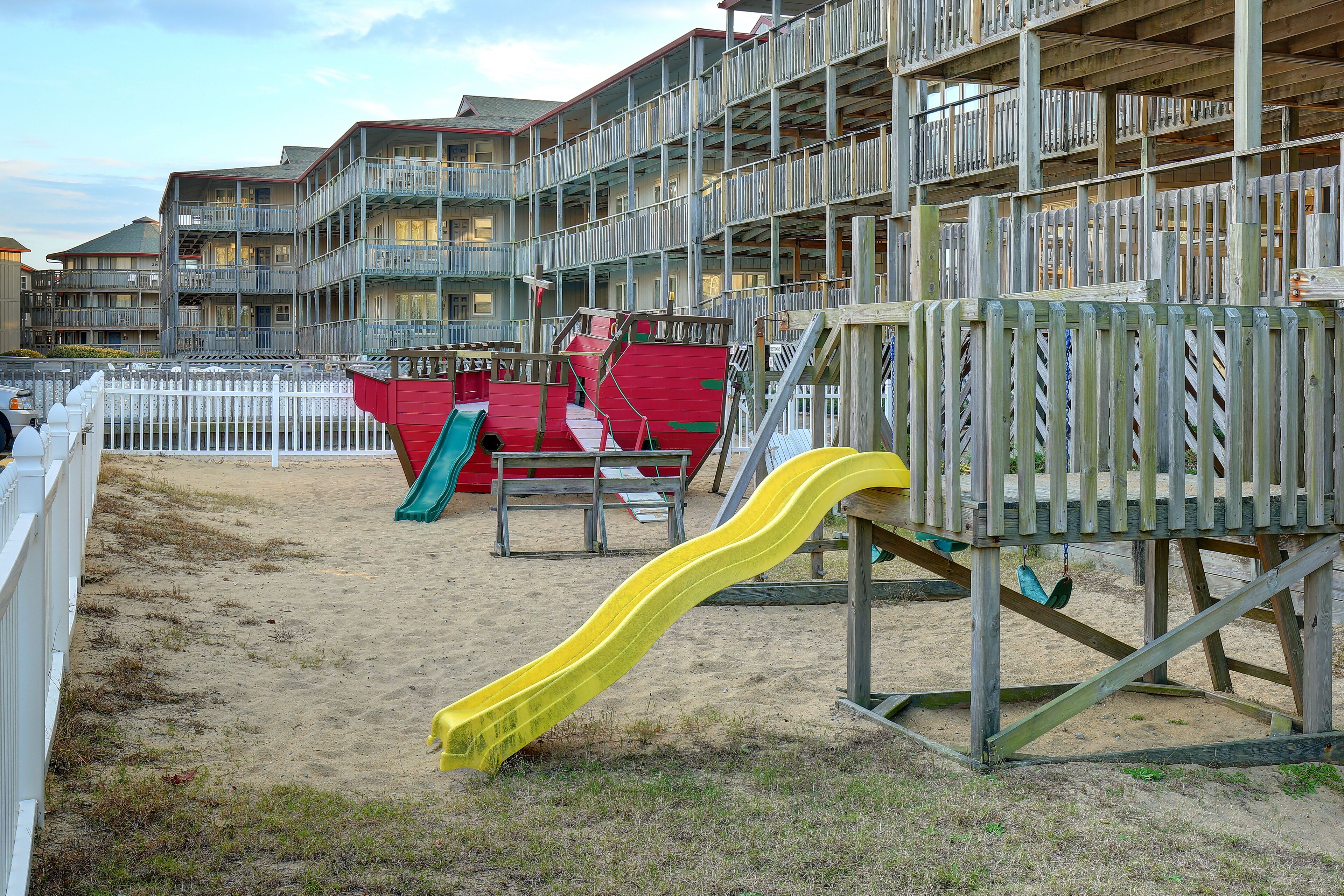 A beachside playground with a yellow slide and red play structures.