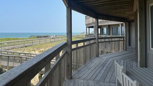 Een houten terras met uitzicht op het strand en de zee.