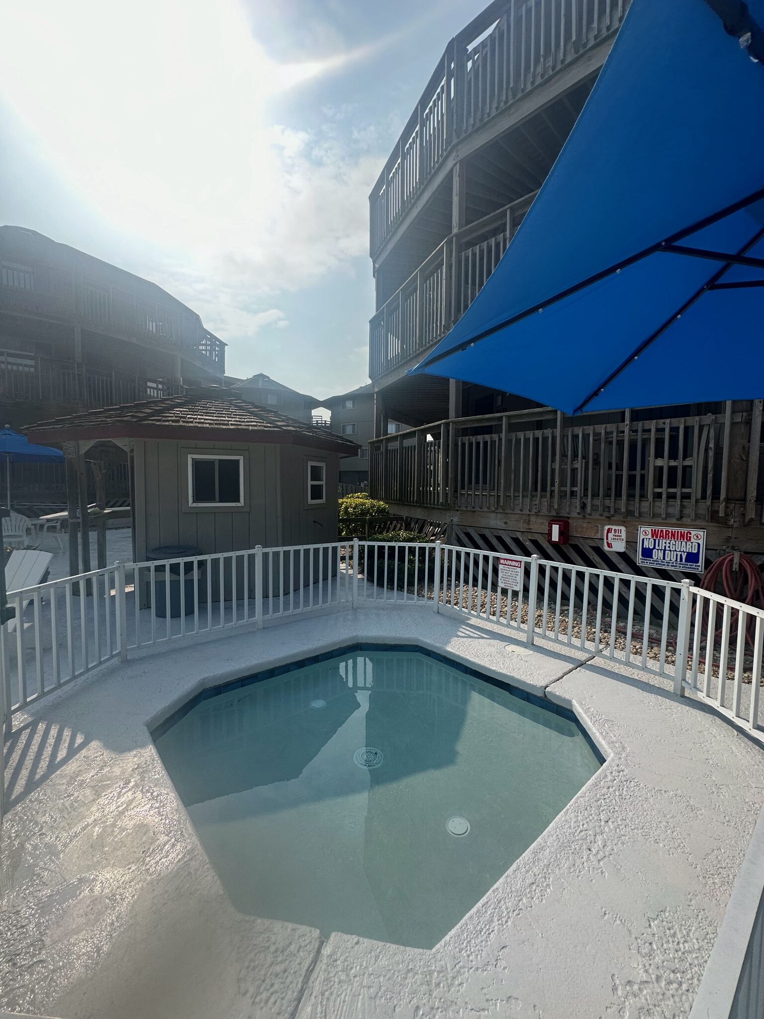 Una piscina con cubierta blanca y una sombrilla azul.