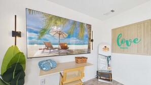 A room with a beach scene painting, a small table with a basket, a bench, and a wall-mounted sign saying 'love shack'.