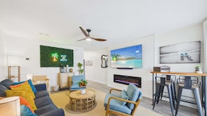 Ein modernes Wohnzimmer mit Flachbildfernseher, Kamin, Deckenventilator und Barbereich.