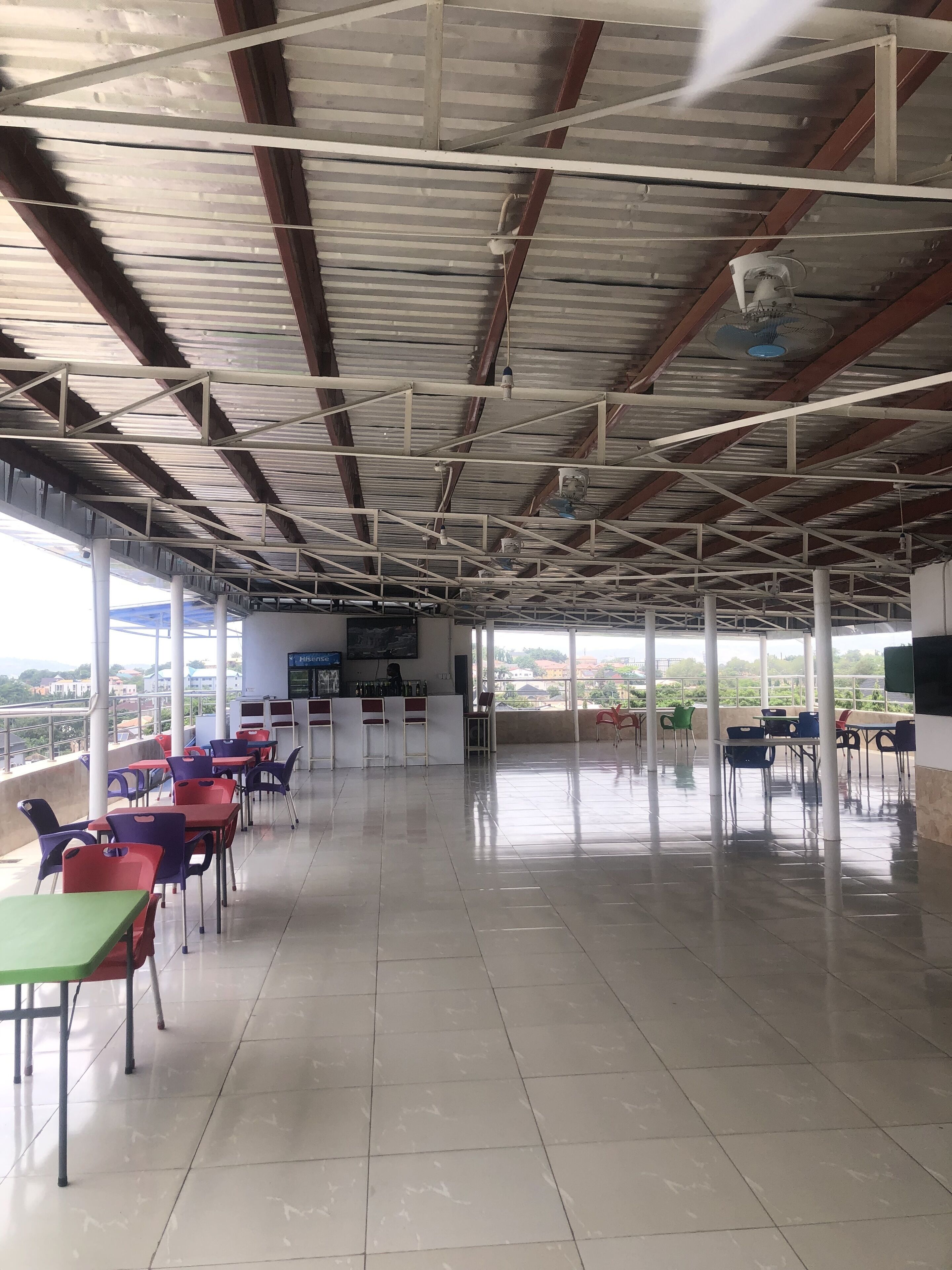 A spacious indoor area with a high ceiling, tiled floor, and multiple tables and chairs.