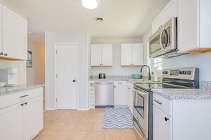 A modern kitchen with white cabinets, a dishwasher, a stove, and a microwave.