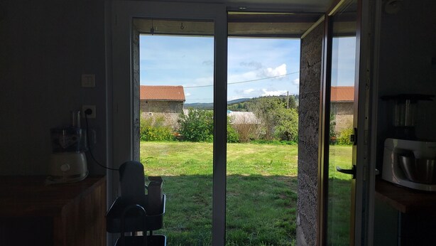 Une cuisine équipée d’un lave-vaisselle intégré, d’une petite table et offrant une vue sur une cour verdoyante grâce à une porte-fenêtre coulissante.