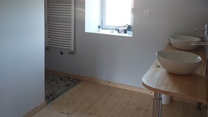Une salle de bain avec une fenêtre, deux lavabos et un plancher en bois.