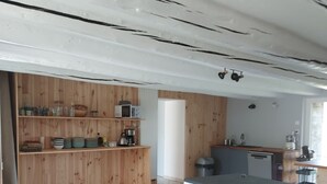Une cuisine avec des meubles de rangement en bois, une table à manger et des tabourets de bar.