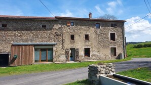 Un bâtiment en pierre avec un toit recouvert de tuiles, une porte en bois et une petite fenêtre.